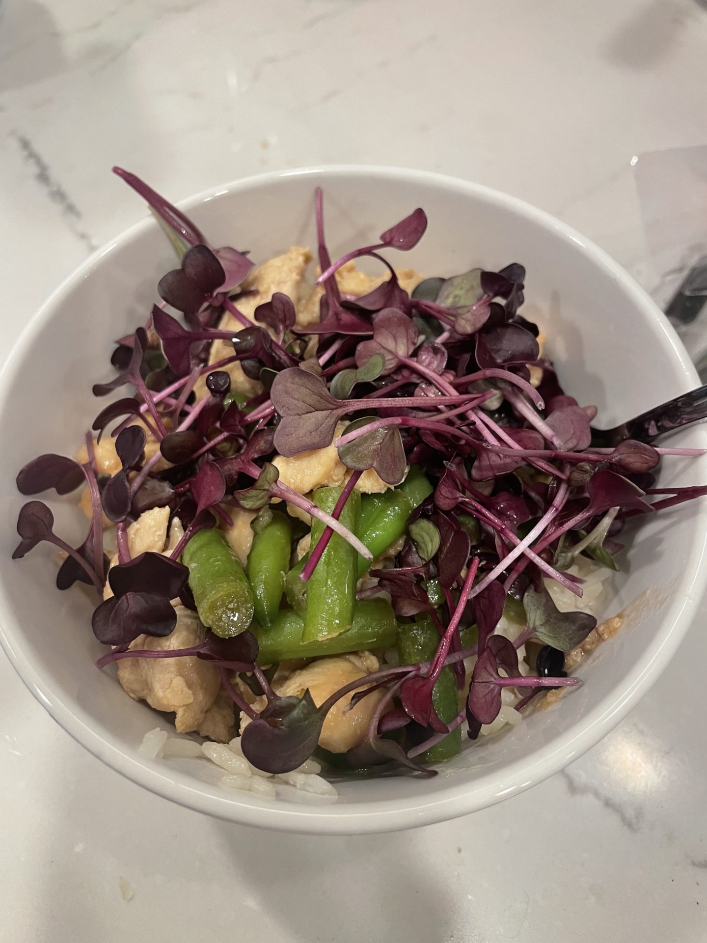 Radish microgreens garnish a meal of honey chicken.