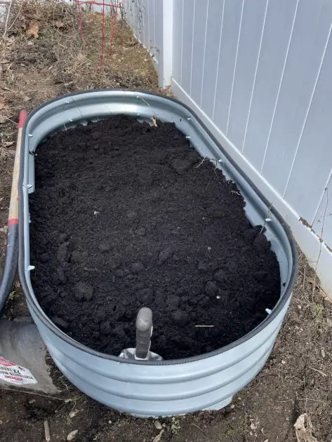 A metal raised bed filled with organic soil.