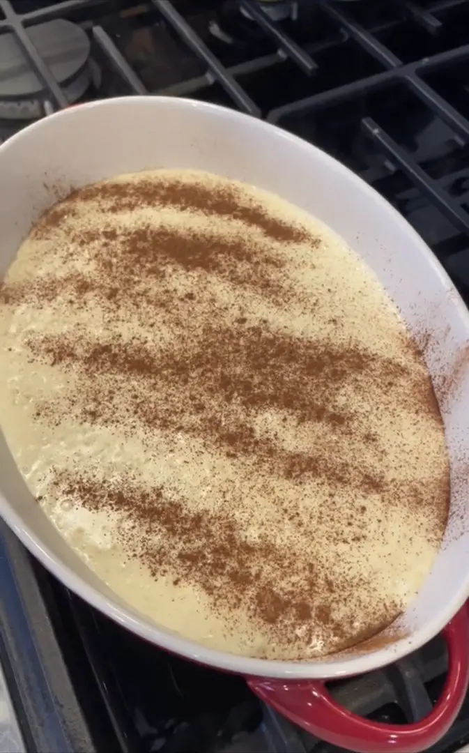 Rice pudding in a serving dish garnished with ground cinnamon.
